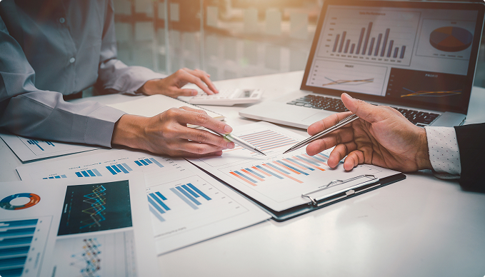 table with different charts printed out and two people reviewing them